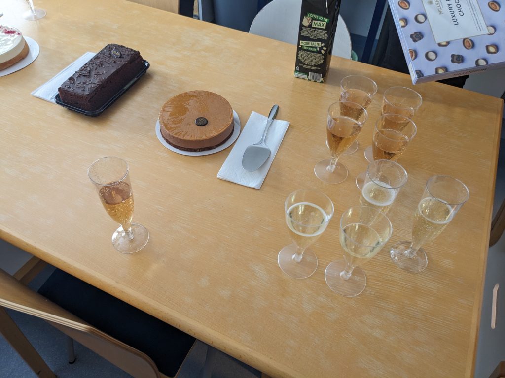 A photo of glasses of bubbly and three cakes.